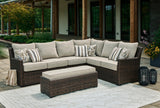 This is a lifestyle image showing the sectional sofa and the cushioned bench on a stone patio next to a house.