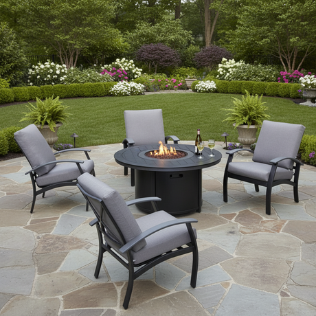 This is a lifestyle image showing four cushioned patio chairs around a circular fire pit table on a stone patio in a grassy backyard.