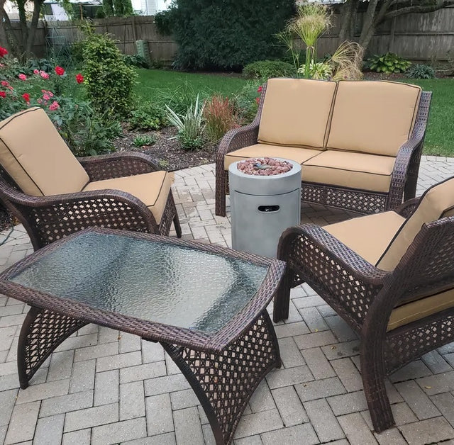 Patio furniture set on a stone patio. The frames are dark brown and the cushions are an orange-ish, tan color.