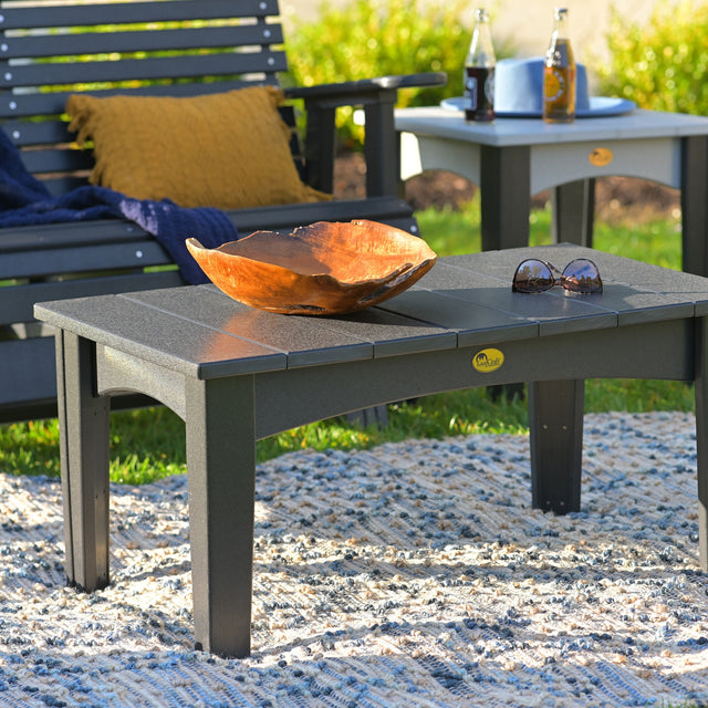 This is a lifestyle image showing the Black colored coffee table in front of a black glider bench.