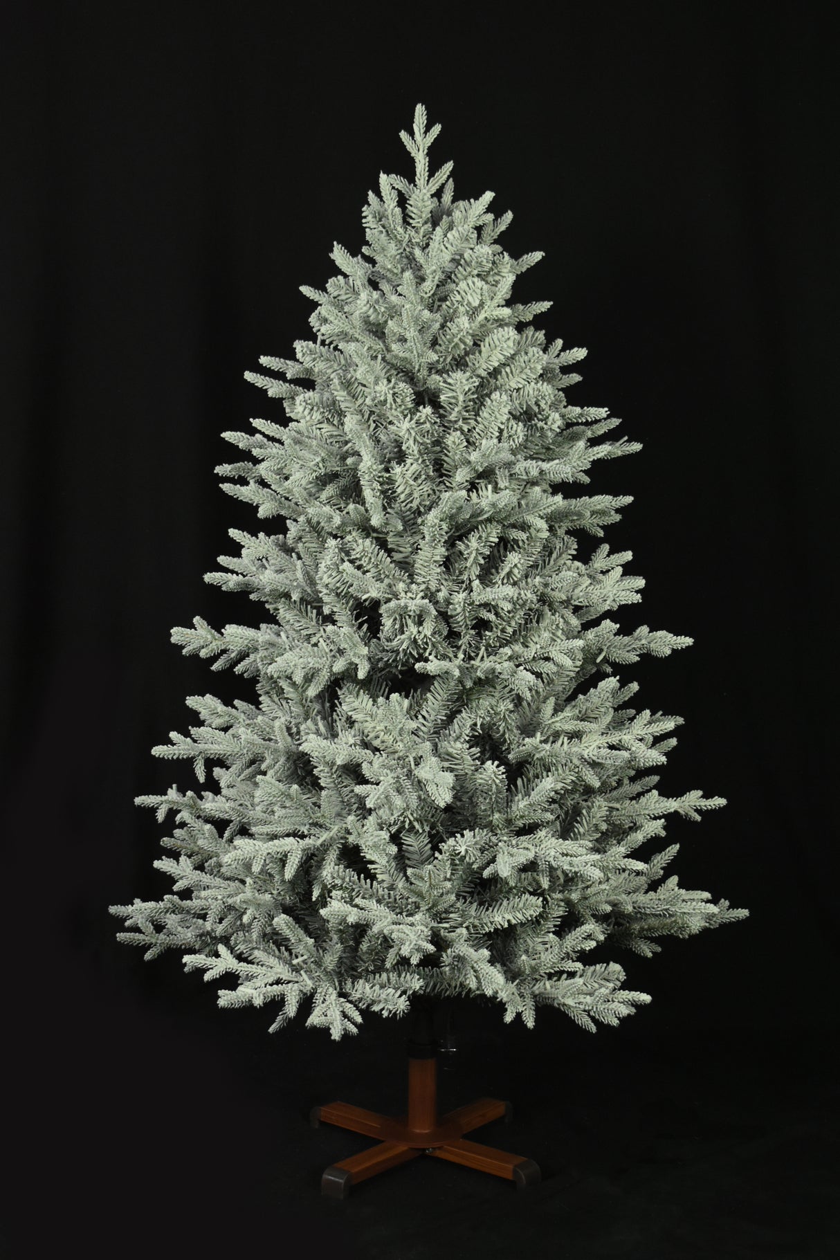 This image shows the flocked Christmas tree with the lights turned off. The tree is up against a black background.