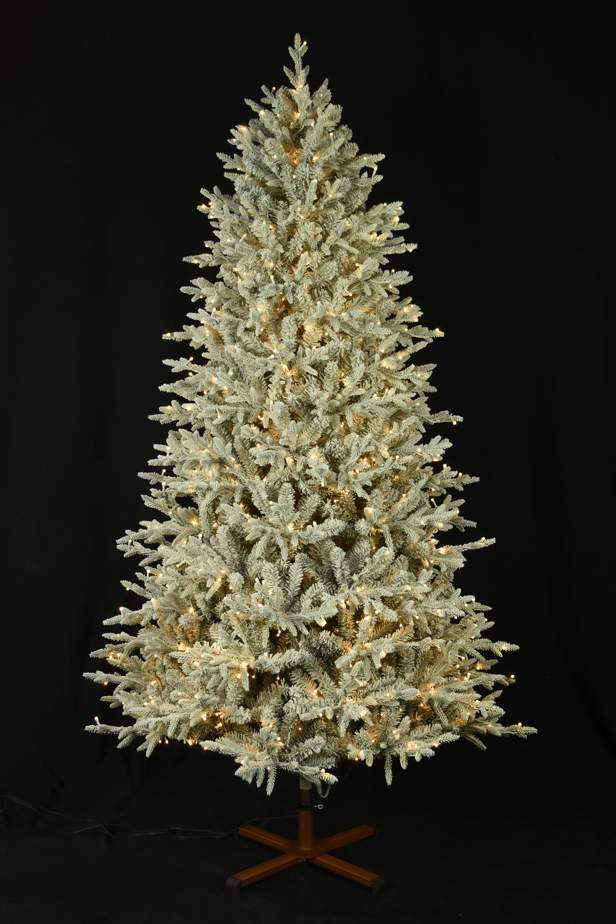 This image shows the flocked Christmas tree pre-lit with Warm White Starry Lights. The tree is up against a black background.