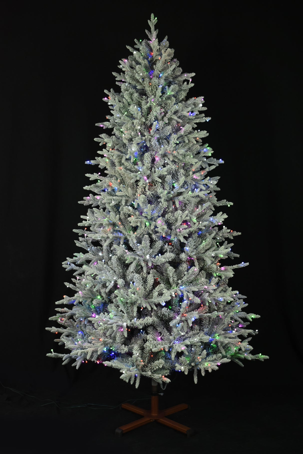 This image shows the flocked Christmas tree pre-lit with Multi-Colored Starry Lights. The tree is up against a black background.