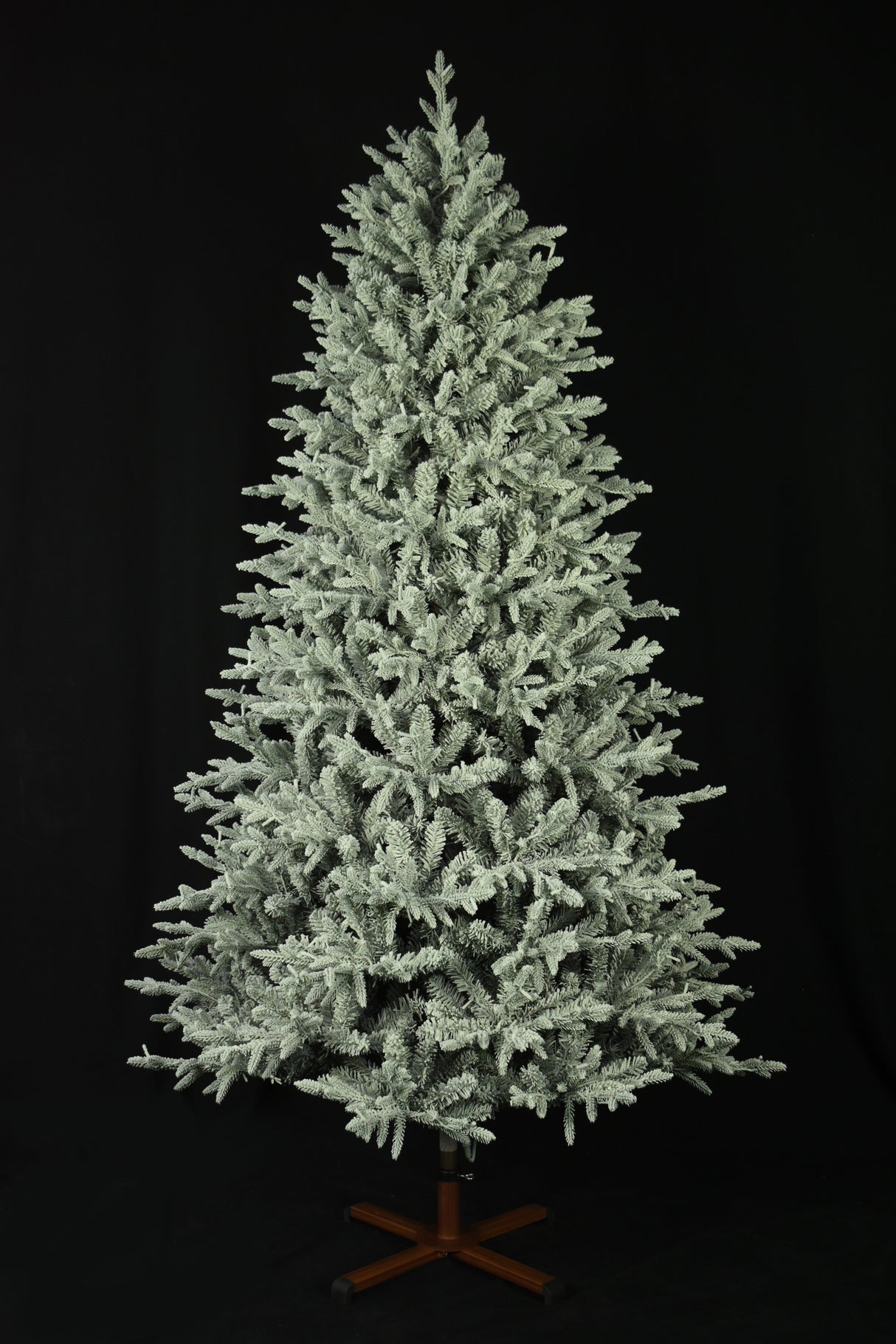 This image shows the flocked Christmas tree with the lights turned off. The tree is up against a black background.