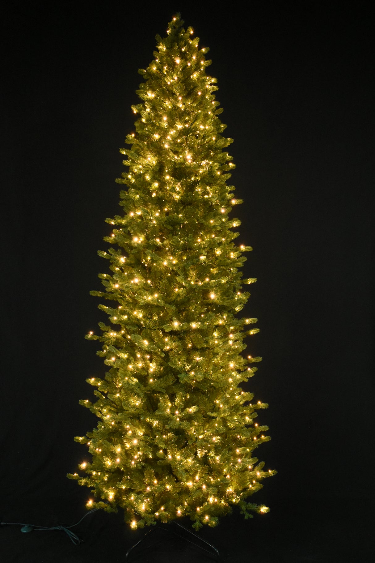 This image shows this specific artificial tree pre-lit with Warm White Starry Lights. This tree is up against a black background.
