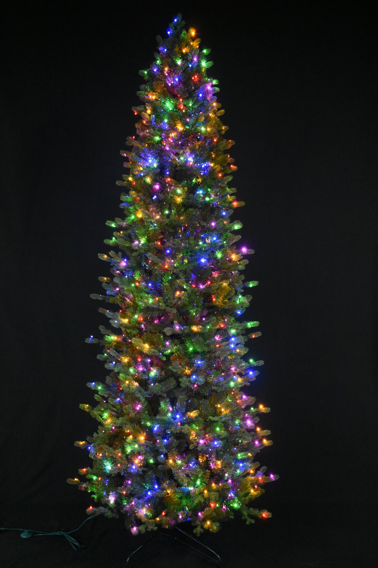 This image shows this specific artificial tree pre-lit with Multi-Colored Starry Lights. This tree is up against a black background.