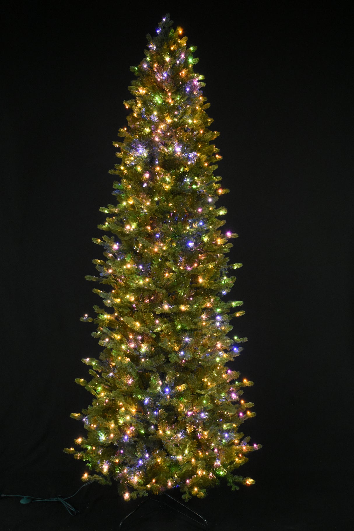 This image shows this specific artificial tree pre-lit with Multi-Colored Starry Lights. This tree is up against a black background.