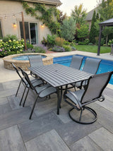 This is a lifestyle image showing this patio dining set on a stone patio next to an in-ground pool.
