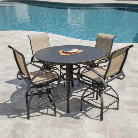 This is a lifestyle image showing this counter height patio furniture set on a stone patio next to an inground swimming pool.