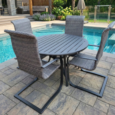This is a lifestyle image showing this wicker spring dining patio set on a stone patio next to an in-ground swimming pool.