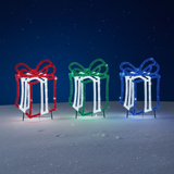 This is a lifestyle image showing the three different present decorations in the snow at night.