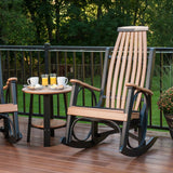 This is a lifestyle image showing two Antique Mahogany and Black colored Grandpa's Rocking Chairs with a matching table between them. They're on a wooden porch in a grassy backyard.