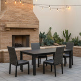 This is a lifestyle image showing this patio dining set on a stone patio next to an outdoor fireplace.