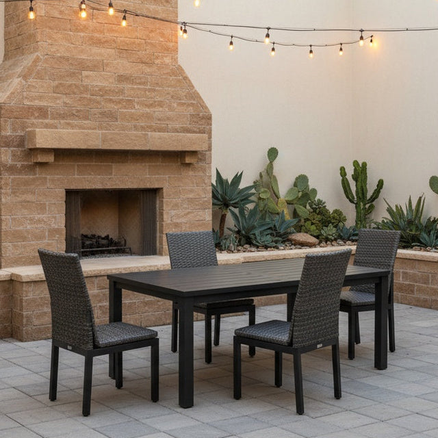 This is a lifestyle image showing this patio dining set on a stone patio next to an outdoor fireplace.