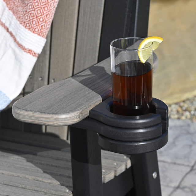 This is a lifestyle image showing the Black colored cup holder added onto the arm of a Coastal Gray and Black colored Adirondack chair.
