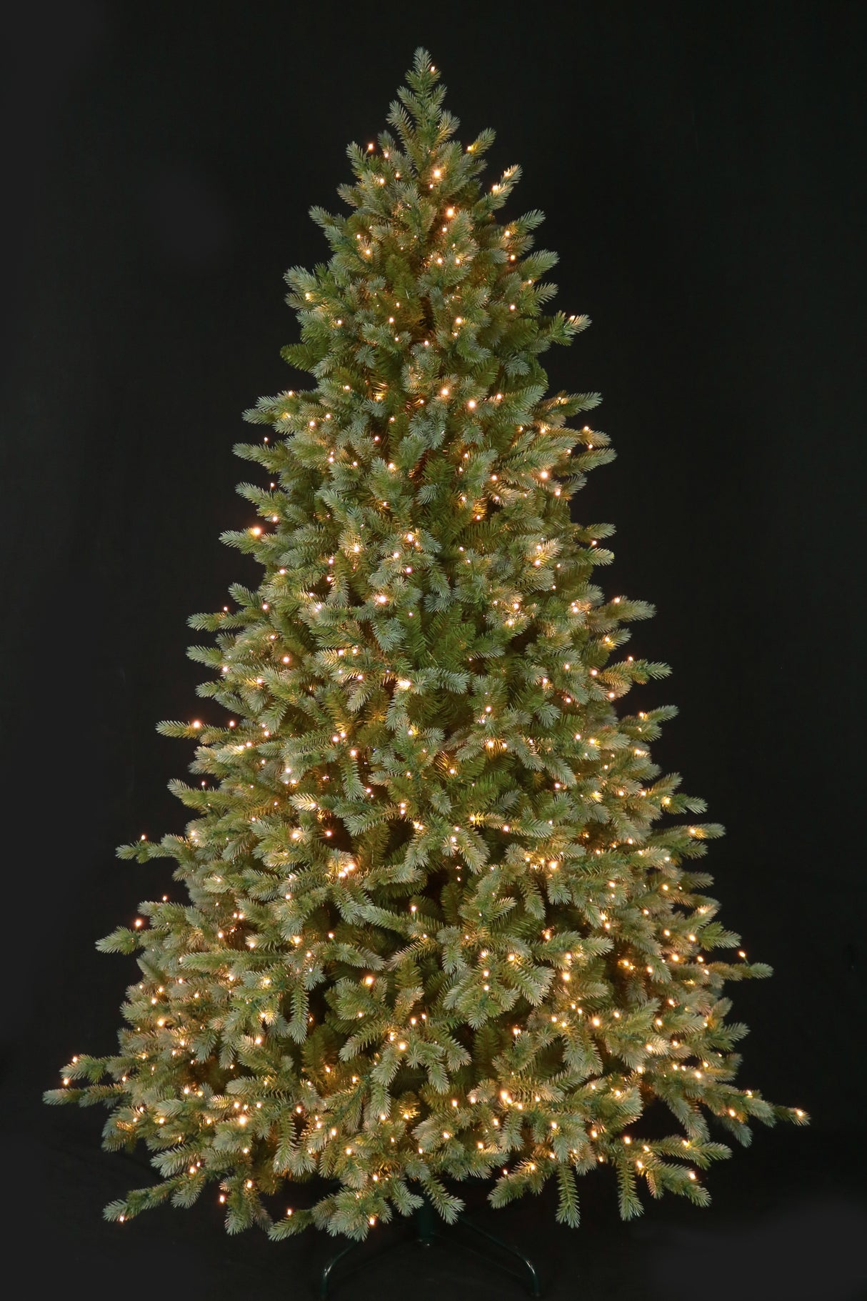 This is an image showing this artificial tree pre-lit with Warm White Starry Lights. This tree is up against a black background.