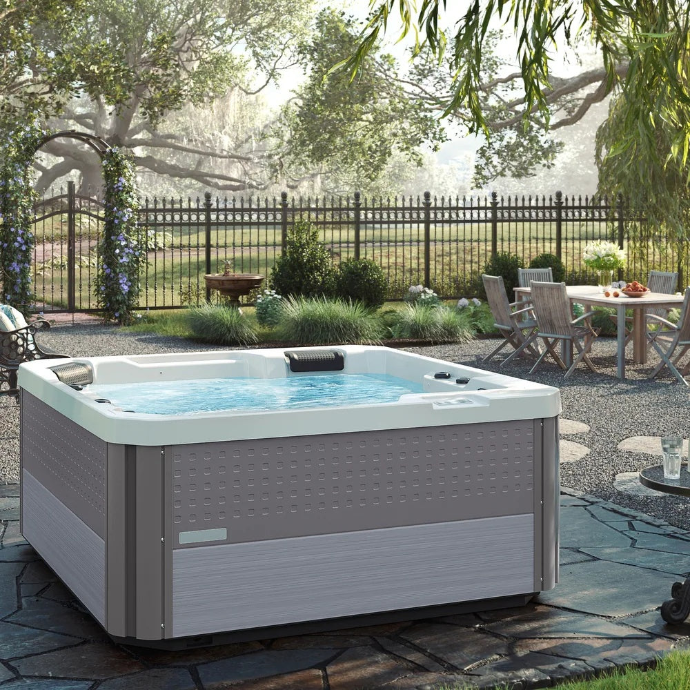 This is a lifestyle image showing the hot tub on a stone patio in a nice backyard.