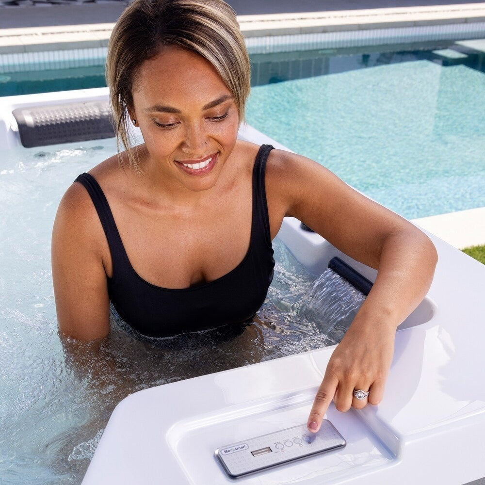 This is a lifestyle image showing a woman controlling the jets in the hot tub by touching a button on the control panel.