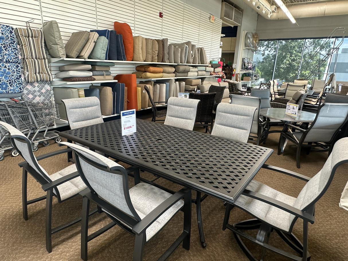 Outdoor furniture set with chairs and a large table displayed in the Tinley Park Outlet store.