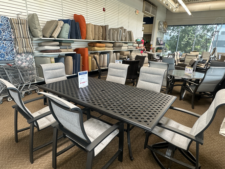 Outdoor furniture set with chairs and a large table displayed in the Tinley Park Outlet store.