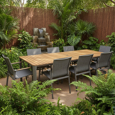 This is a lifestyle image showing this specific patio dining set in a backyard full of blooming plants and a fun waterfall feature.