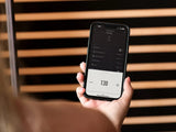 This image shows a person checking the controls for the sauna on a phone.