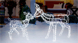 This animated image shows the fawn and the doe wire sculptures kissing noses on a snowy front lawn.
