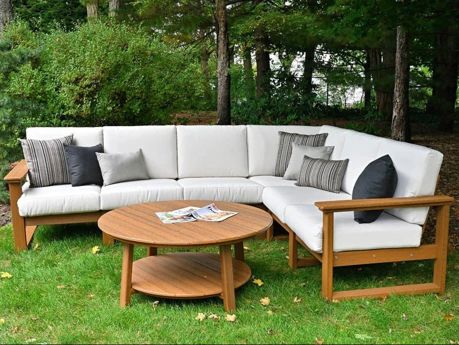 This is a lifestyle image showing the deep seating sectional set in a grassy backyard. The frames are antique mahogany and the cushions are canvas.
