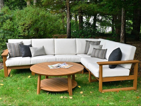 This is a lifestyle image showing the deep seating sectional set in a grassy backyard. The frames are antique mahogany and the cushions are canvas.