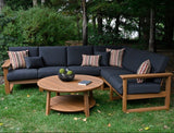 This is a lifestyle image showing the deep seating sectional set in a grassy backyard. The frames are antique mahogany and the cushions are spectrum carbon.