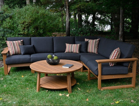 This is a lifestyle image showing the deep seating sectional set in a grassy backyard. The frames are antique mahogany and the cushions are spectrum carbon.