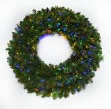 This image shows an artificial pine wreath on a white background pre-lit with multi-colored lights.