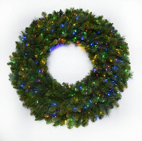 This image shows an artificial pine wreath on a white background pre-lit with multi-colored lights.