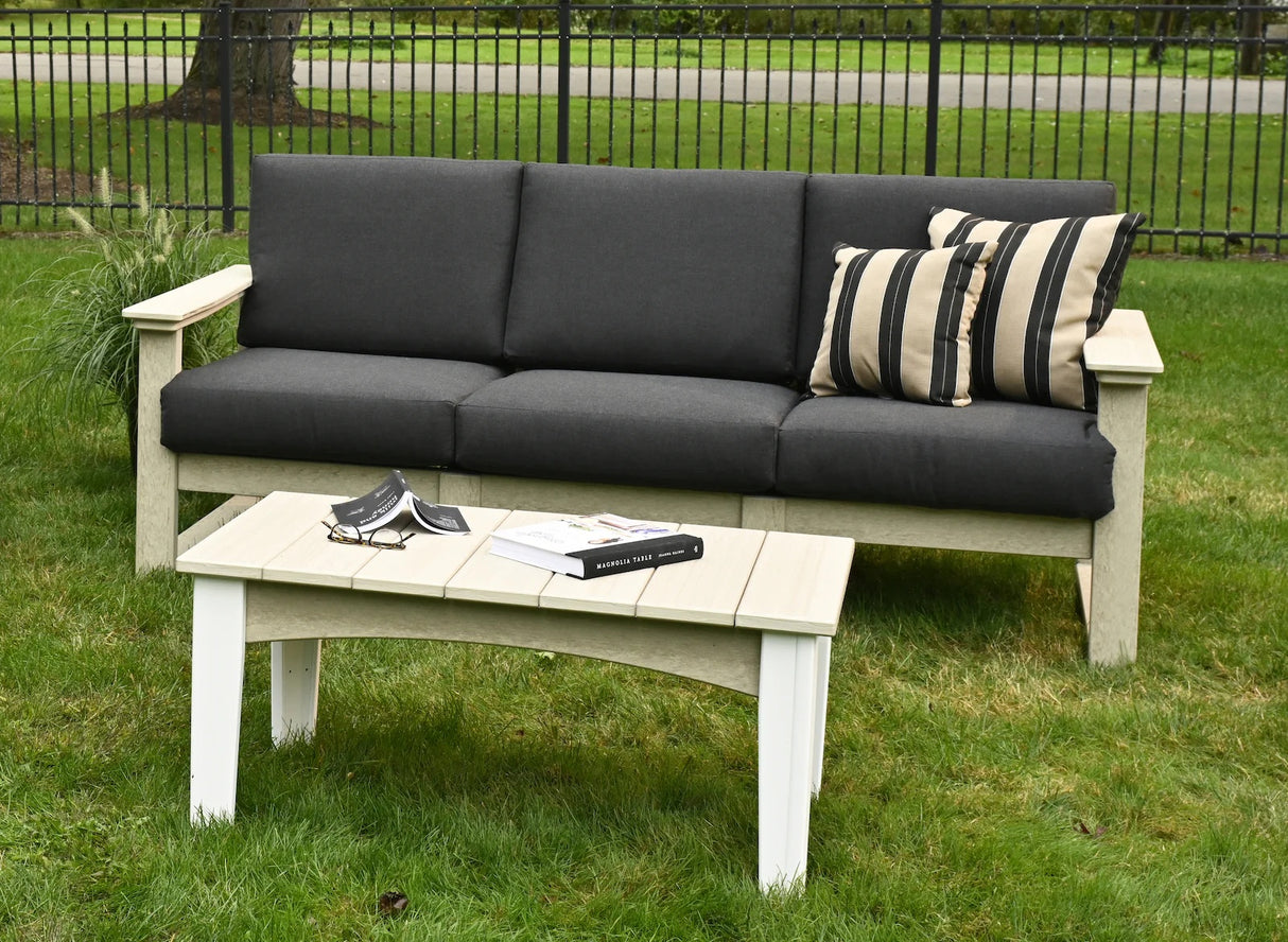 This is a lifestyle image showing this deep seating sofa in a grassy backyard. The frames of the sofa are birch and the cushions are spectrum carbon.