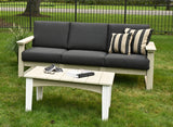 This is a lifestyle image showing this deep seating sofa in a grassy backyard. The frames of the sofa are birch and the cushions are spectrum carbon.