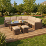 This is a lifestyle image showing this outdoor sectional sofa, coffee table and two square ottomans on a wooden porch in a backyard full of pretty flowers and bushes.