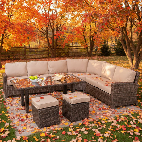 This is a lifestyle image showing this wicker cushioned sectional sofa, coffee table and two ottomans in a nice yard on a sunny, fall day.