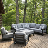 This is a lifestyle image showing the light gray and dark gray colored patio furniture set on a wooden deck on the side of a log cabin. There are hanging lights and trees in the background.