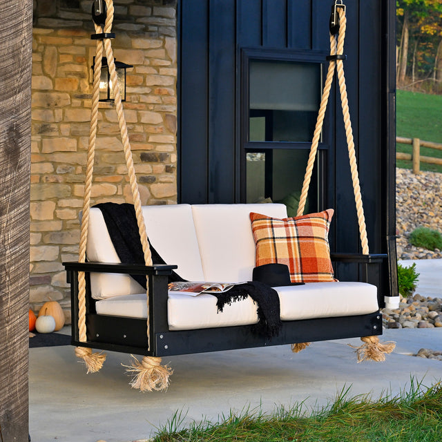 This is a lifestyle image showing the Lanai Deep Seating Loveseat Swing with Black frames and Canvas colored cushions.
