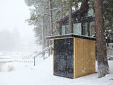 This is a lifestyle image showing the sauna outside of a house during a snowstorm.