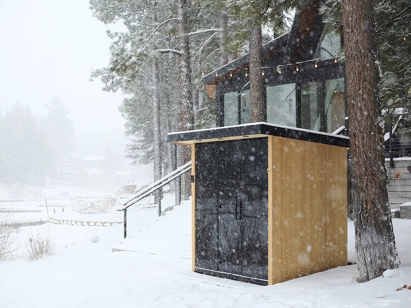 This is a lifestyle image showing the sauna outside of a house during a snowstorm.
