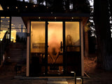 This is a lifestyle image showing the sauna outside of someone's house. There are two people inside and the windows are fogged up.