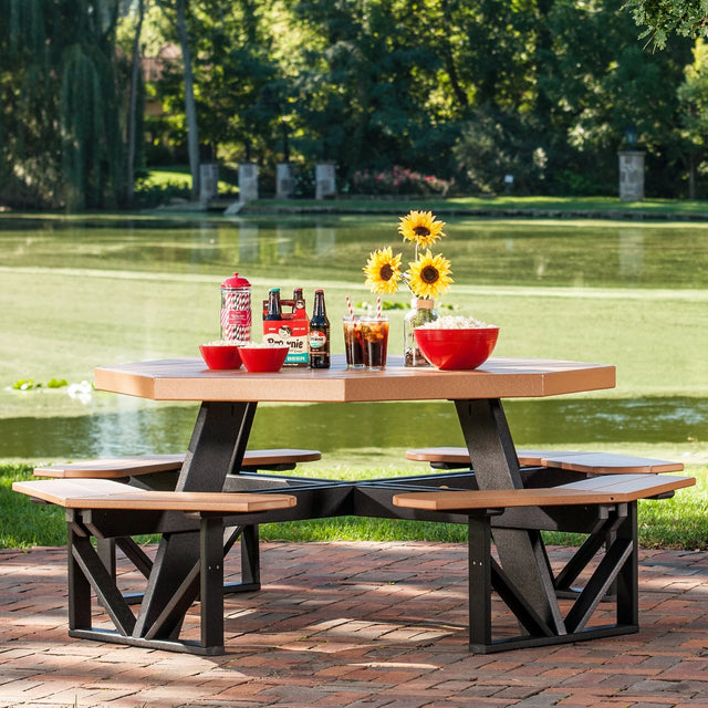 This is a lifestyle image showing the Cedar and Black colored picnic table with attached benches. This table is on a brick patio next to a pond.