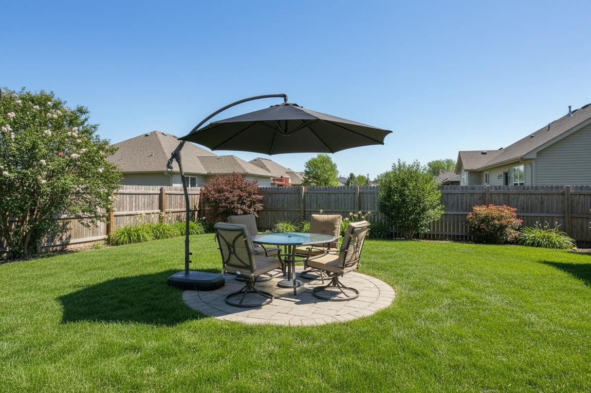 This image shows a grassy backyard with a small, circular stone patio in the center. In the circle there's a patio set with an umbrella over it, offering shade.