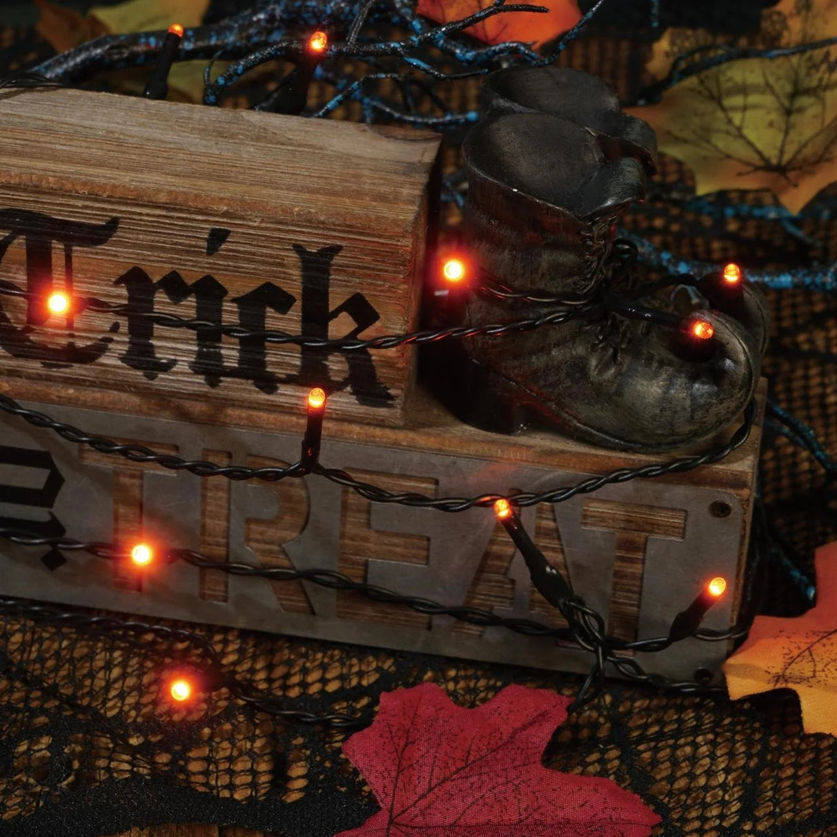 This is a lifestyle image showing the orange starry lights draped around tabletop Halloween decorations.