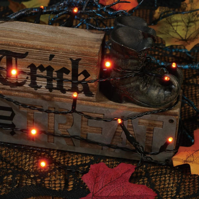 This is a lifestyle image showing the orange starry lights draped around tabletop Halloween decorations.