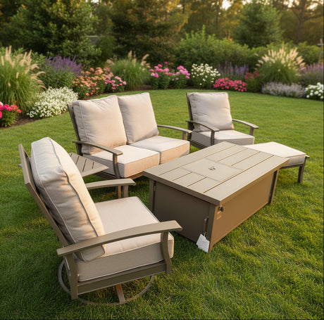 This is a lifestyle image showing this cushioned outdoor furniture set in a grassy backyard surrounded by pretty flowers on a sunny day.