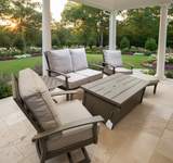This is a lifestyle image showing this cushioned furniture set on an outdoor patio surrounded by pretty flowers.