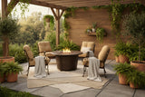 This is a lifestyle image showing the tan and brown colored furniture set on an outdoor patio surrounded by potted trees and ferns.