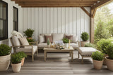 This is a lifestyle image showing this patio furniture collection on a covered balcony. There are lots of potted plants and a cute plush stuffed animal on the chair.